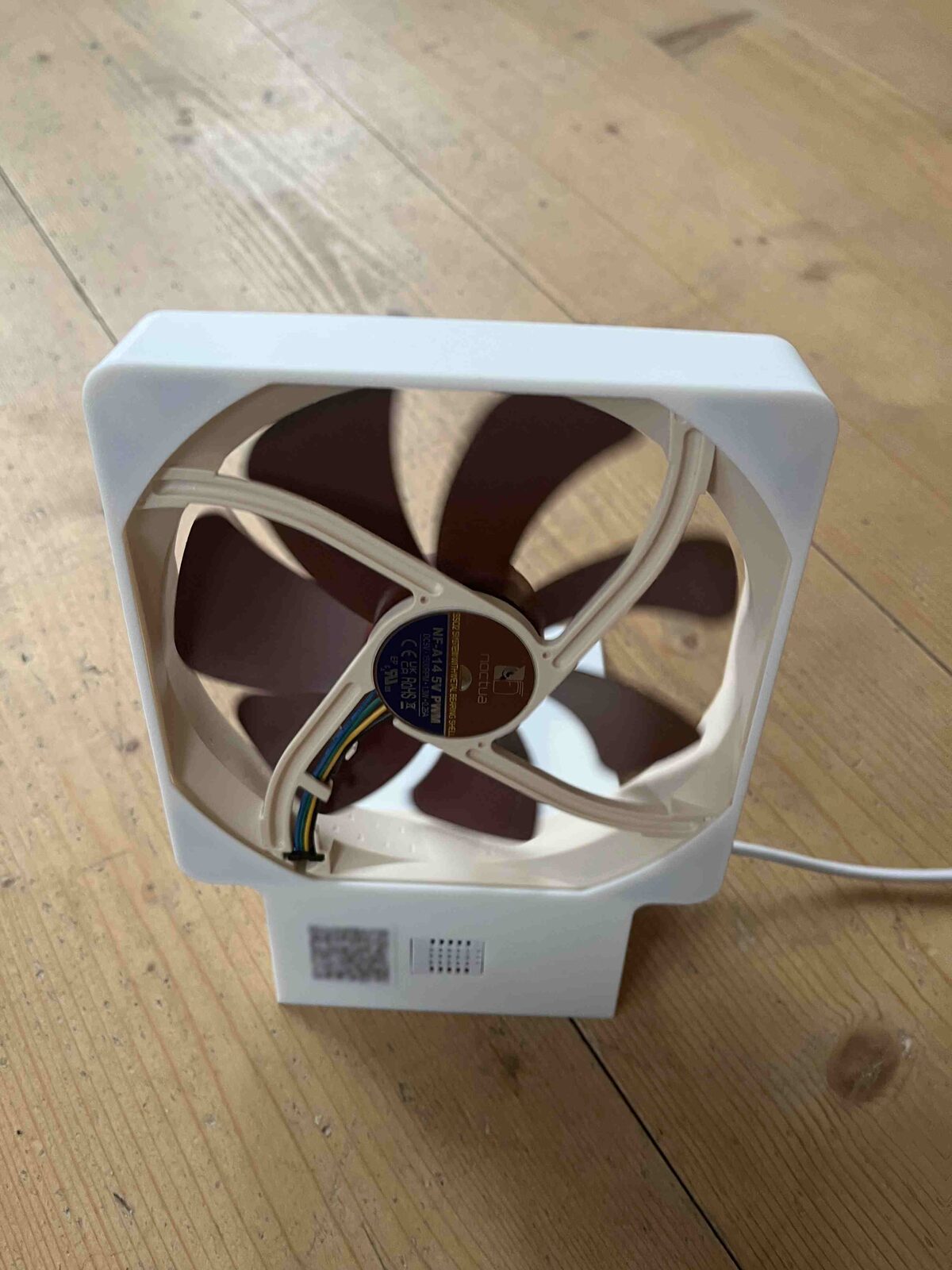 The assembled smart fan: a Noctua NF-A14 5V PWM fan in the 3D-printed housing, standing on a wooden floor, with a vent for the sensor